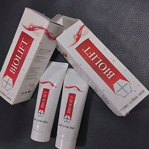Dve rdeče-beli škatlici in dve tubi kreme Biolift na sivi tkanini
