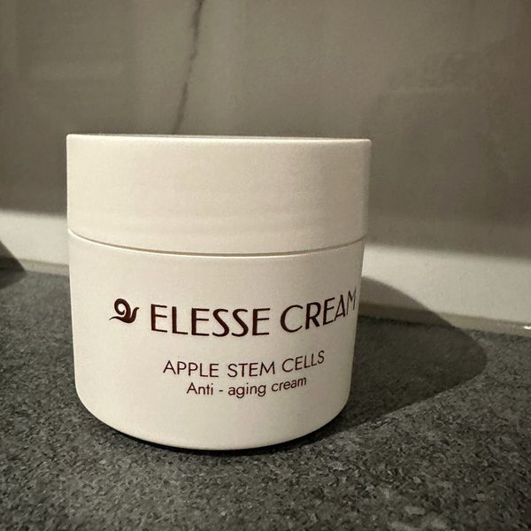 Bel lonček Elesse Cream z napisom Apple Stem Cells na temnem kamnu