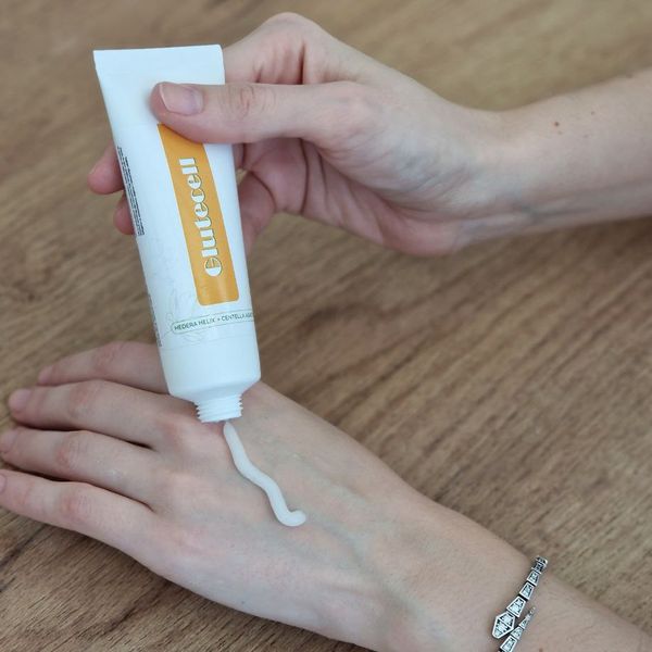 Krema iz belo-oranžne tube Glutecell, iztisnjena na hrbtno stran dlani
