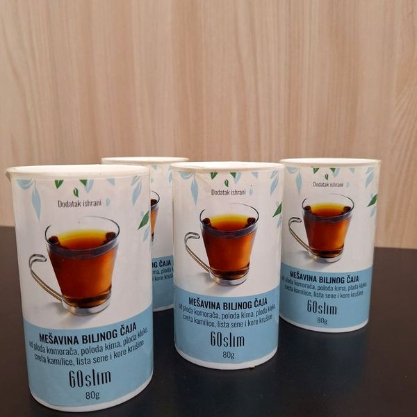 Tri bele doze zeliščnega čaja GoSlim s sliko skodelice na temni mizi