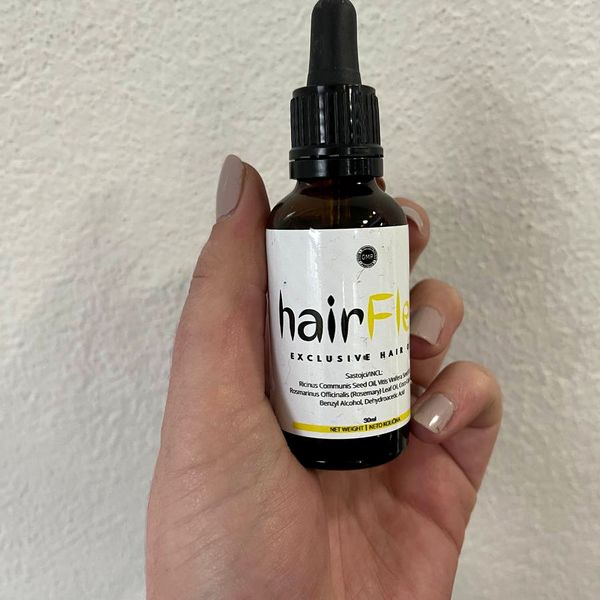 Roka drži rjavo stekleničko s kapalko hairFlex exclusive hair oil