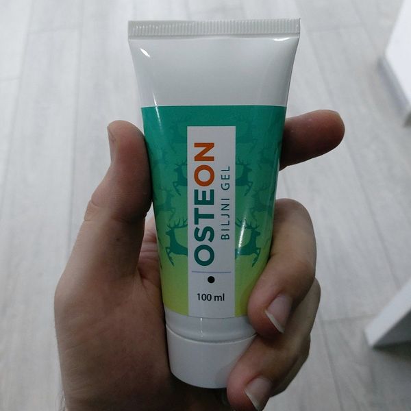 Roka drži tubo Osteon biljni gel, 100 ml, z zelenim vzorcem jelena